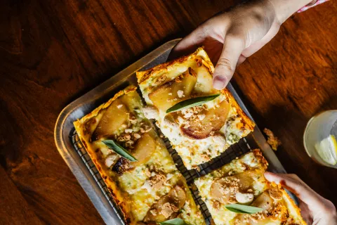 Una mano tomando porciones de pizza.