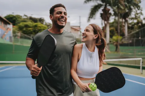 Dos personas con paletas y pelotas de pickeball