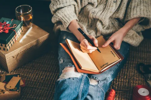 Mujer escribiendo metas en libro.