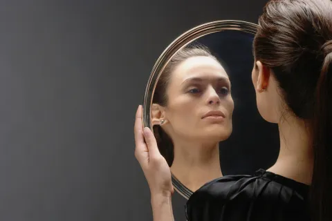 Foto de mujer mirándose en un espejo.