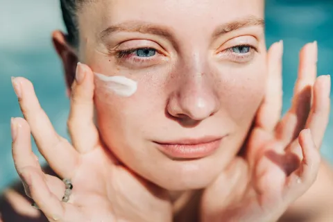 Una mujer poniendose una crema en la cara