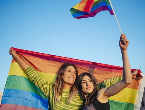 dos mujeres con una bandera de la diversidad sexual