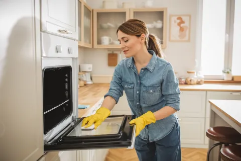 Una mujer limpiando el horno