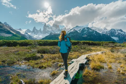 Una mujer vestida con ropa de trekking en un sendero cercano a las montañas.