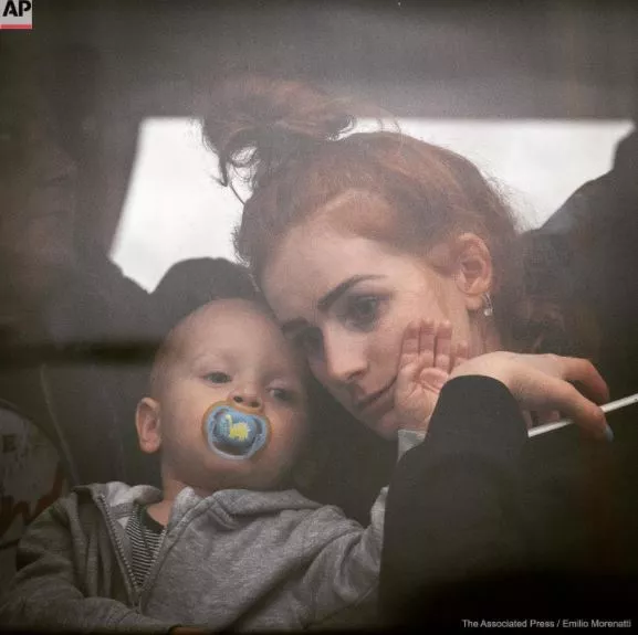 Una mujer sostiene a su bebé dentro de un autobús cuando salen de Kiev, Ucrania, el jueves 24 de febrero de 2022